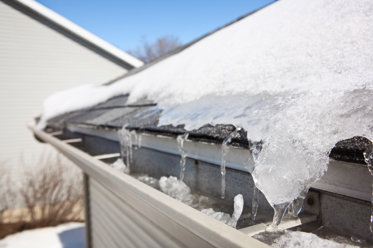 Ice building up on a Minneapolis roof gutter — the winter failure mode that damages gutters, fascia, and interior ceilings